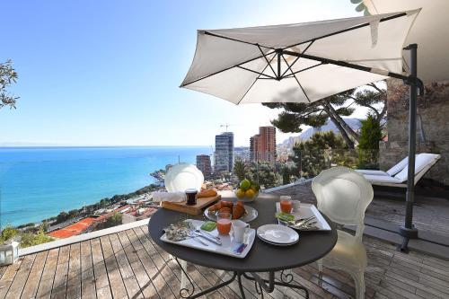 - une table avec de la nourriture et un parasol sur le balcon dans l'établissement Villa Laetitia Private Pool, à Roquebrune-Cap-Martin