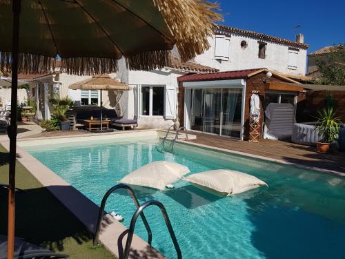 une piscine avec deux coussins et un parasol dans l'établissement Tropical Couple, à Marignane