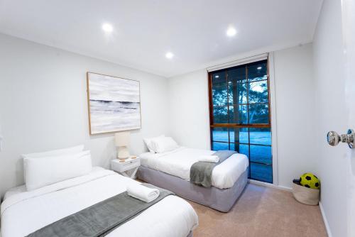 a white room with two beds and a window at Farm Stay Picturesque views in Balhannah
