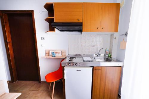 a small kitchen with a sink and a red chair at Dionisos Roses in Paralia Dionysiou