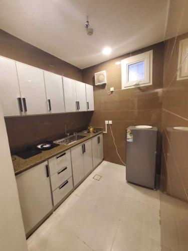a small kitchen with white cabinets and a refrigerator at رست بست للشقق المخدومة in Al Mikhlaf