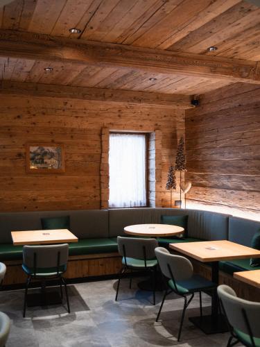 a restaurant with wooden walls and tables and chairs at FIORI Dolomites Experience Hotel in San Vito di Cadore