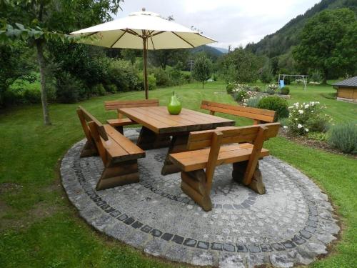a picnic table and benches with an umbrella at Tolles Appartement in Marktgemeinde Übelbach mit Garten in Übelbach