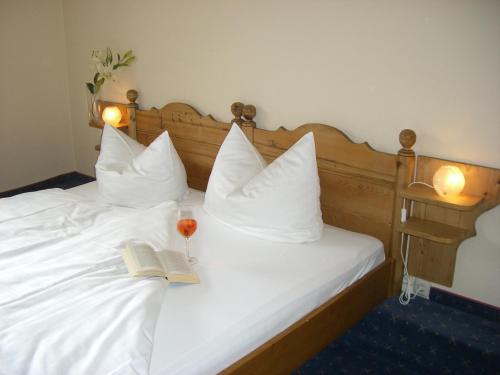 a bed with a book and a glass of wine on it at Pension Kellerer in Raubling