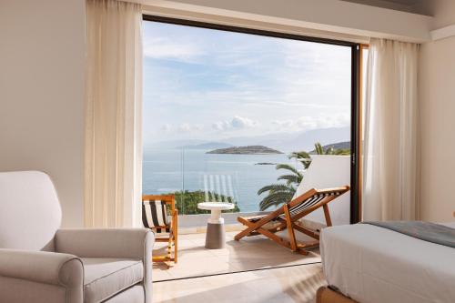 a bedroom with a view of the ocean at St. Nicolas Bay Resort Hotel & Villas in Agios Nikolaos