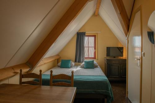 a attic bedroom with a bed and a table at Hotel Groede in Groede