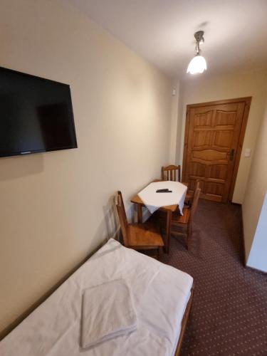 a room with a bed and a table and a television at Willa pod Smrekiem in Białka Tatrzanska
