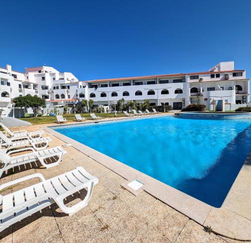 a swimming pool with lounge chairs in front of a building at Apartamento da Praia in Sagres