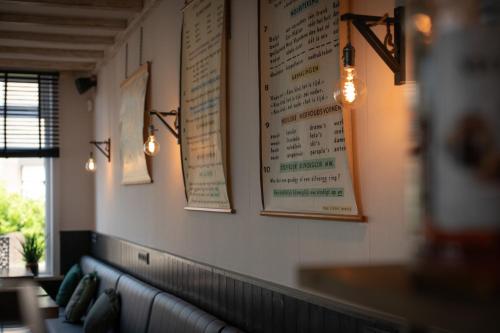 a wall with menus and lights on a restaurant at Hotel Groede in Groede