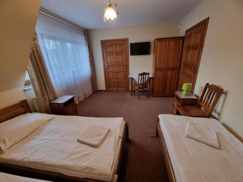 a bedroom with two beds and a table and chairs at Willa pod Smrekiem in Białka Tatrzanska