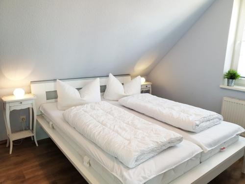 a white bed with white sheets and pillows on it at Ferienhaus Achtern Diek in Schönberg