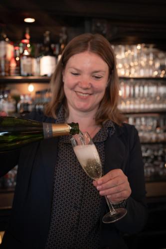 a woman is holding a glass of wine at Hotel Groede in Groede