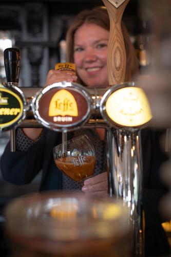 a woman holding a bar with a glass of beer at Hotel Groede in Groede