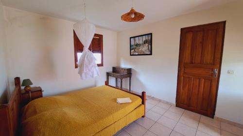 a bedroom with a bed and a wooden door at Le Pavillon des Alizés in Gourbeyre