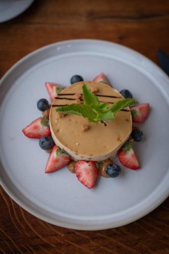 a white plate with a dessert with strawberries and blueberries at Hotel Groede in Groede