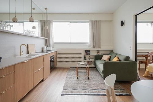 Il comprend une cuisine et un salon avec un canapé vert. dans l'établissement Appartement moderne et chic proche Tour Eiffel, à Paris