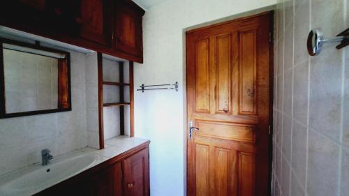 a bathroom with a sink and a wooden door at Le Pavillon des Alizés in Gourbeyre