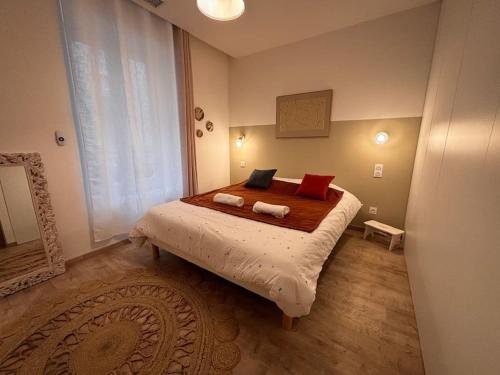 une chambre avec un grand lit avec des oreillers rouges dans l'établissement Bel appartement centre-ville, à Saint-Étienne
