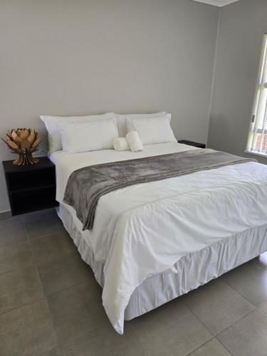 a bedroom with a large bed with white sheets and pillows at Airport Fresh Lodge in Boksburg