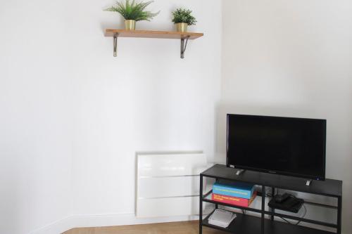 un salon avec une télévision à écran plat sur une étagère dans l'établissement Practical and pleasant 20 m studio, à Montreuil