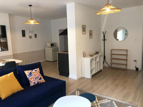 ein Wohnzimmer mit einer blauen Couch und einer Küche in der Unterkunft Les 4 vents in Belfort