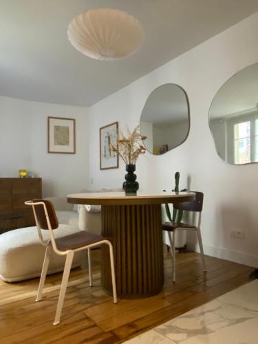- une salle à manger avec une table et deux miroirs dans l'établissement Appartement neuf design - Montmartre, à Paris