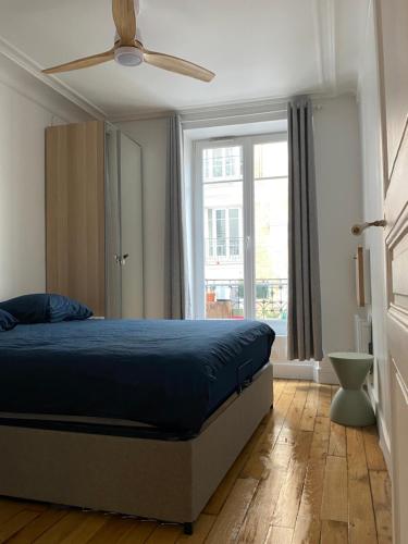 une chambre avec un lit et un ventilateur de plafond dans l'établissement Appartement neuf design - Montmartre, à Paris