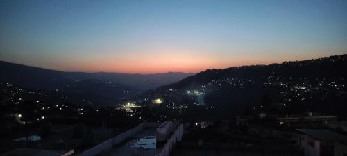a view of the sun setting over a city at Limewood homestay in Almora