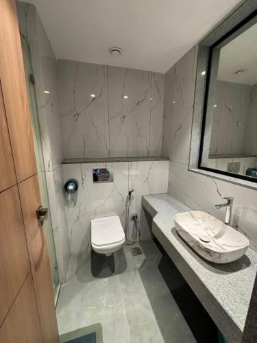 a bathroom with a toilet and a sink and a mirror at RED CARPET CLASSIC HOSPITALITY LLP in Māndvi