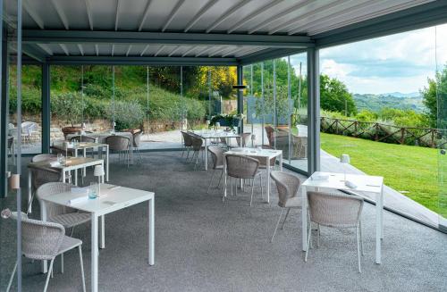 a restaurant with white tables and chairs and windows at Nikis Resort in Gubbio