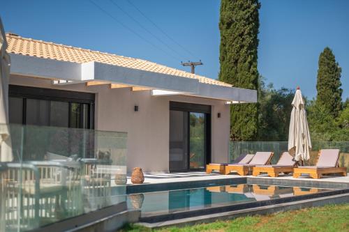 a house with a swimming pool and an umbrella at Villa Danai in Gouvia