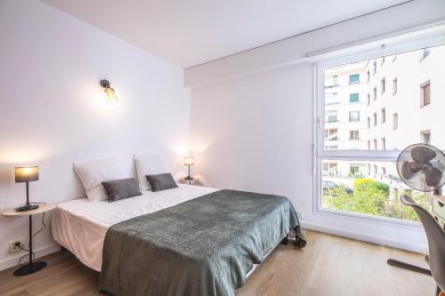 une chambre avec un lit et une grande fenêtre dans l'établissement Appartement Moderne au Cœur d'Annecy - À Deux Pas du Lac et de la Vieille Ville, à Annecy