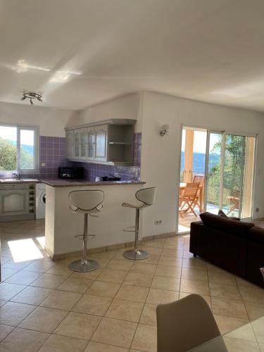 - une cuisine et un salon avec un comptoir et des tabourets dans l'établissement Maison près de Coti-Chiavari, à Coti-Chiavari