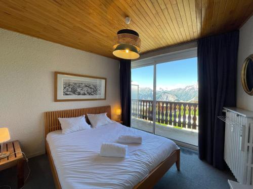 une chambre avec un lit et une grande fenêtre dans l'établissement Homency - Résidence de l'Oisans C5, à L'Alpe-d'Huez