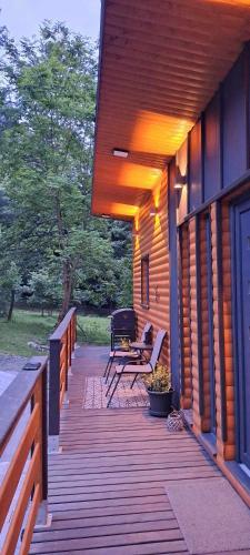 a porch of a house with a bench and a grill at Szalonka Vendégház Kemence in Kemence