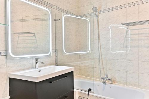 une salle de bain avec un lavabo, un miroir et une baignoire dans l'établissement Appartement Haussmannien lumineux et central, à Paris