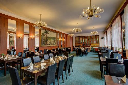 a dining room with tables and chairs and a chandelier at Parkhotel Skalní město in Jičín