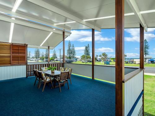 a room with a table and chairs on a balcony at Beachside at Brooms in Brooms Head