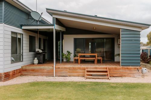 a house with a wooden deck with a table on it at Soulty Vibes in Coffin Bay