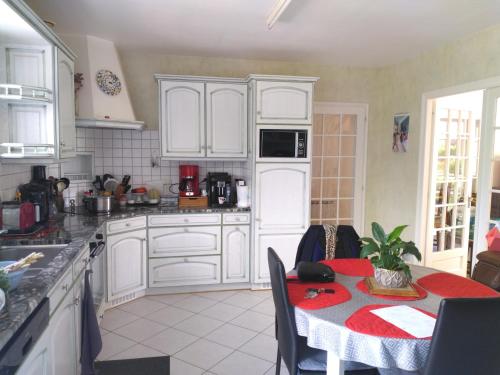 une cuisine avec des placards blancs et une table avec un chiffon rouge dans l'établissement Familly, à Avrillé