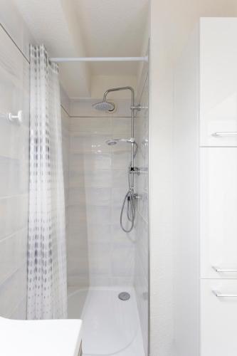 une salle de bain blanche avec douche et toilettes dans l'établissement Chez Fabienne - Superbe appartement avec vue sur la mer et parking, à La Grande Motte