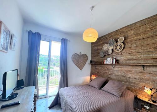 - une chambre avec un mur en bois, un lit et une télévision dans l'établissement L'Oasis 2 chambres en bords de mer, à Propriano