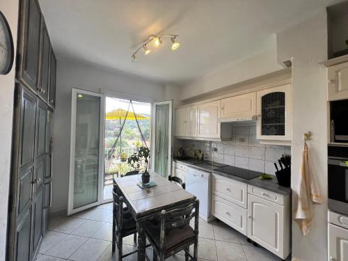 une cuisine avec des armoires blanches et une table à l'intérieur dans l'établissement L'Oasis 2 chambres en bords de mer, à Propriano