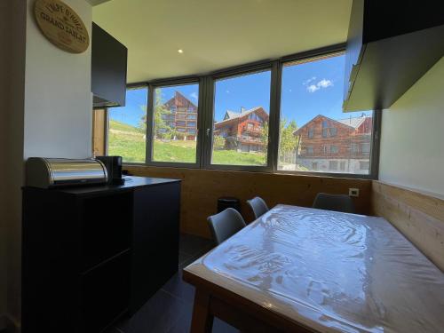 - une cuisine avec une table, des chaises et des fenêtres dans l'établissement Homency - Résidence de l'Oisans F1, à L'Alpe-d'Huez
