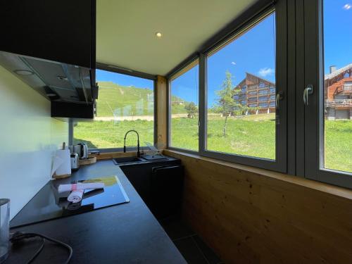 - une cuisine avec de grandes fenêtres et un comptoir avec un évier dans l'établissement Homency - Résidence de l'Oisans F1, à L'Alpe-d'Huez
