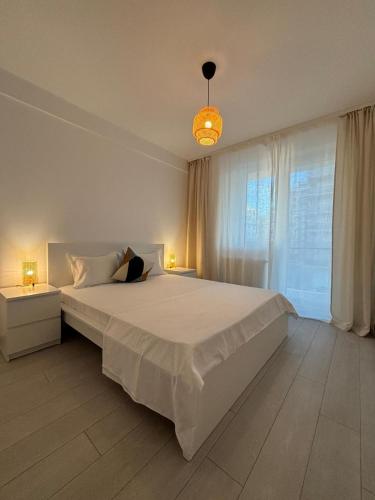 a white bedroom with a large bed and two lamps at Velvet Breeze Apartment in Năvodari