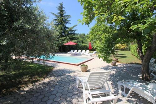 a pool with white chairs and a table and trees at Bungalow Melisa mit Pool in Porec in Poreč