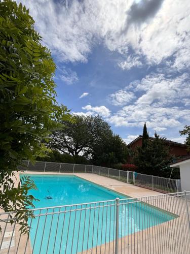 une piscine bleue entourée d'une clôture dans l'établissement Charmant appartement Toulouse, à Toulouse