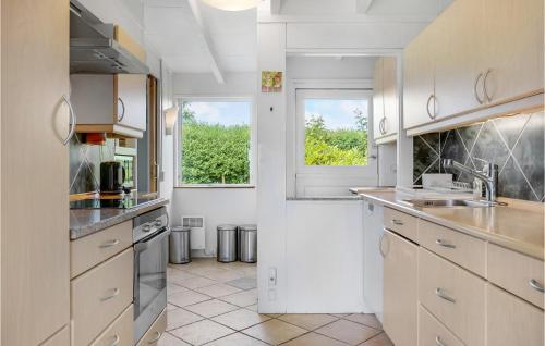 a white kitchen with a sink and a window at Holiday Home Holbæk 39 With Hot Tub in Holbæk