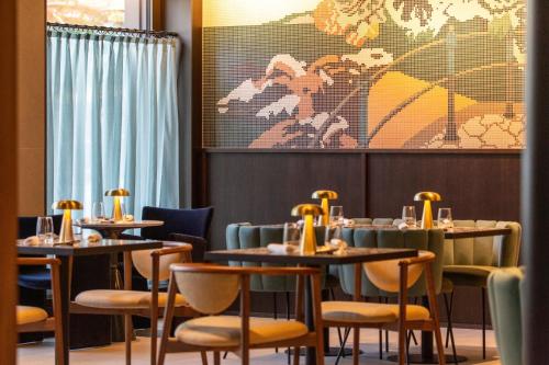a dining room with tables and chairs and a painting at Keight Hotel Opatija, Curio Collection By Hilton in Opatija